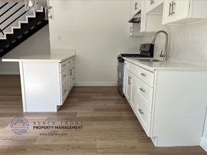 Gardena apartment for rent - A kitchen with white cabinets and a black staircase.